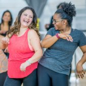 Two women bump hips while dancing.