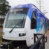 A colorful tram with snowflake designs is parked at a station.