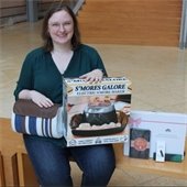 Woman sitting on a bench in a large room, holding a smores maker pack.