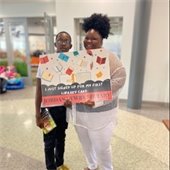 Two library patrons hold a big cardboard rectangle library card that states "I just signed up for my first library card!"